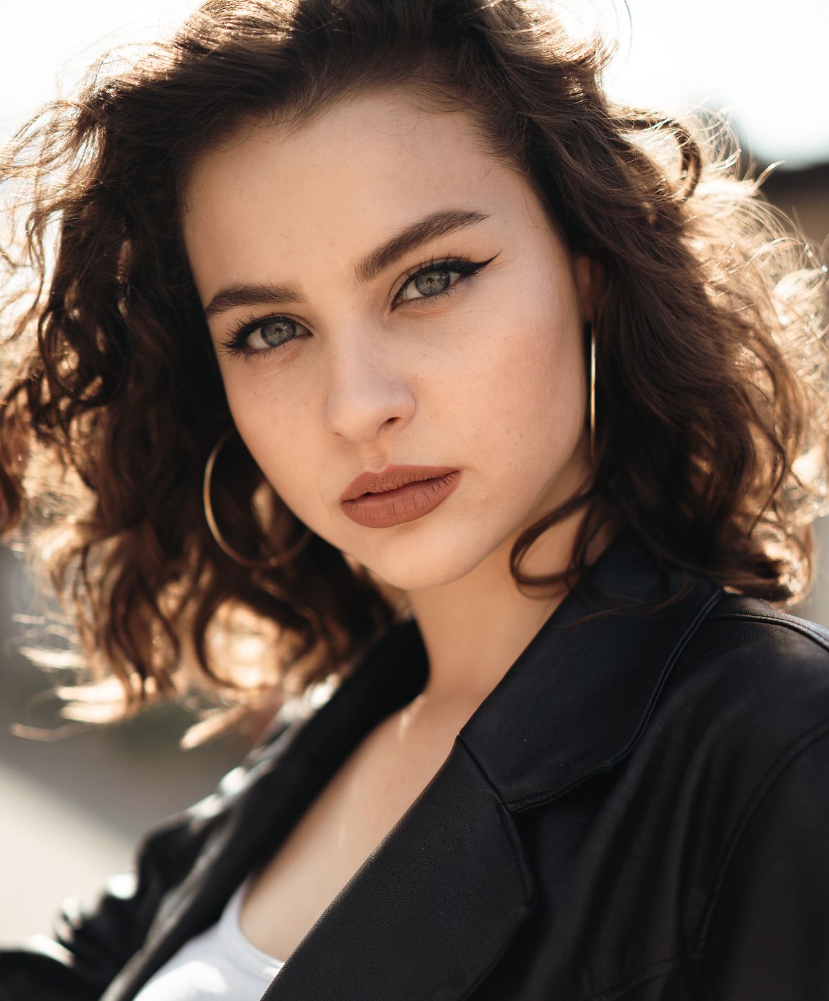 Woman with curly hair and dramatic makeup.