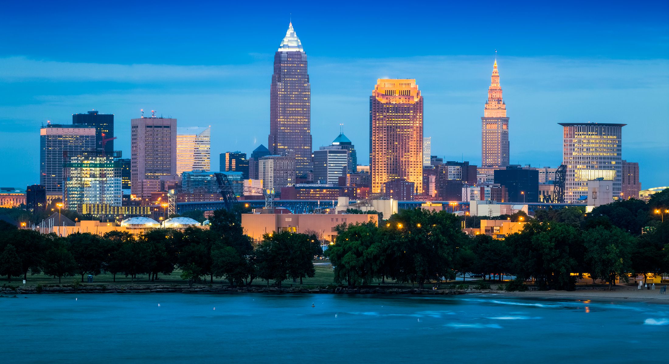 Cleveland skyline at dusk near a waterfront.