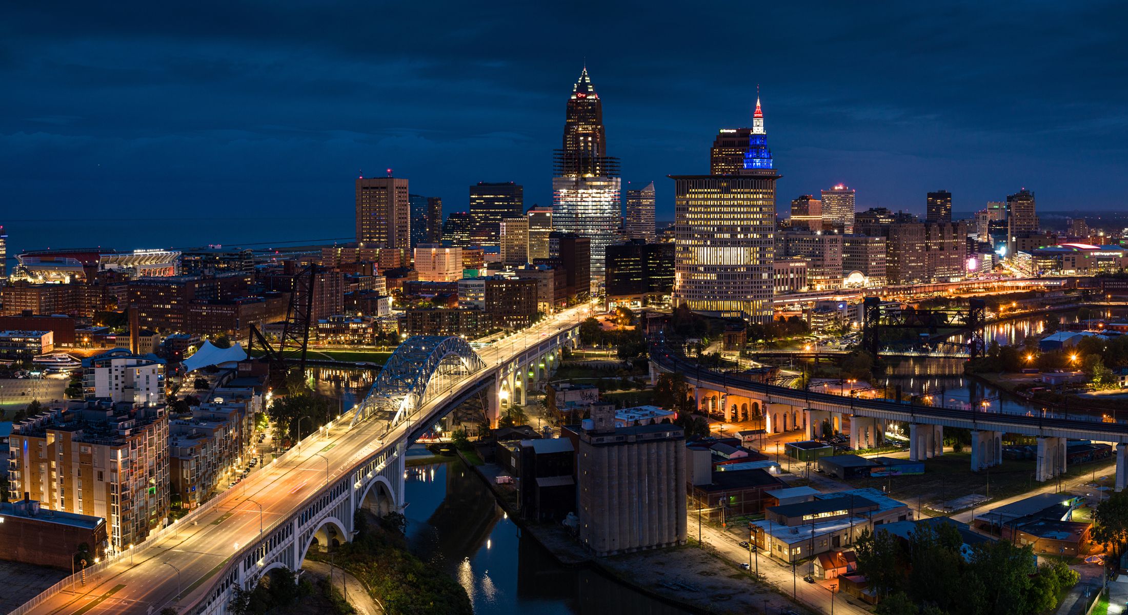 Cleveland skyline illuminated at night with bridges.