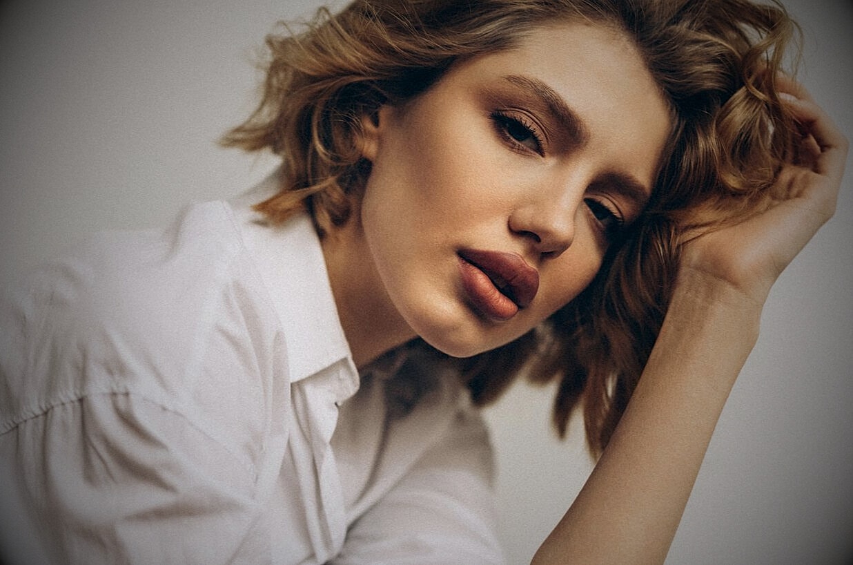 Woman with wavy hair in white shirt, close-up.