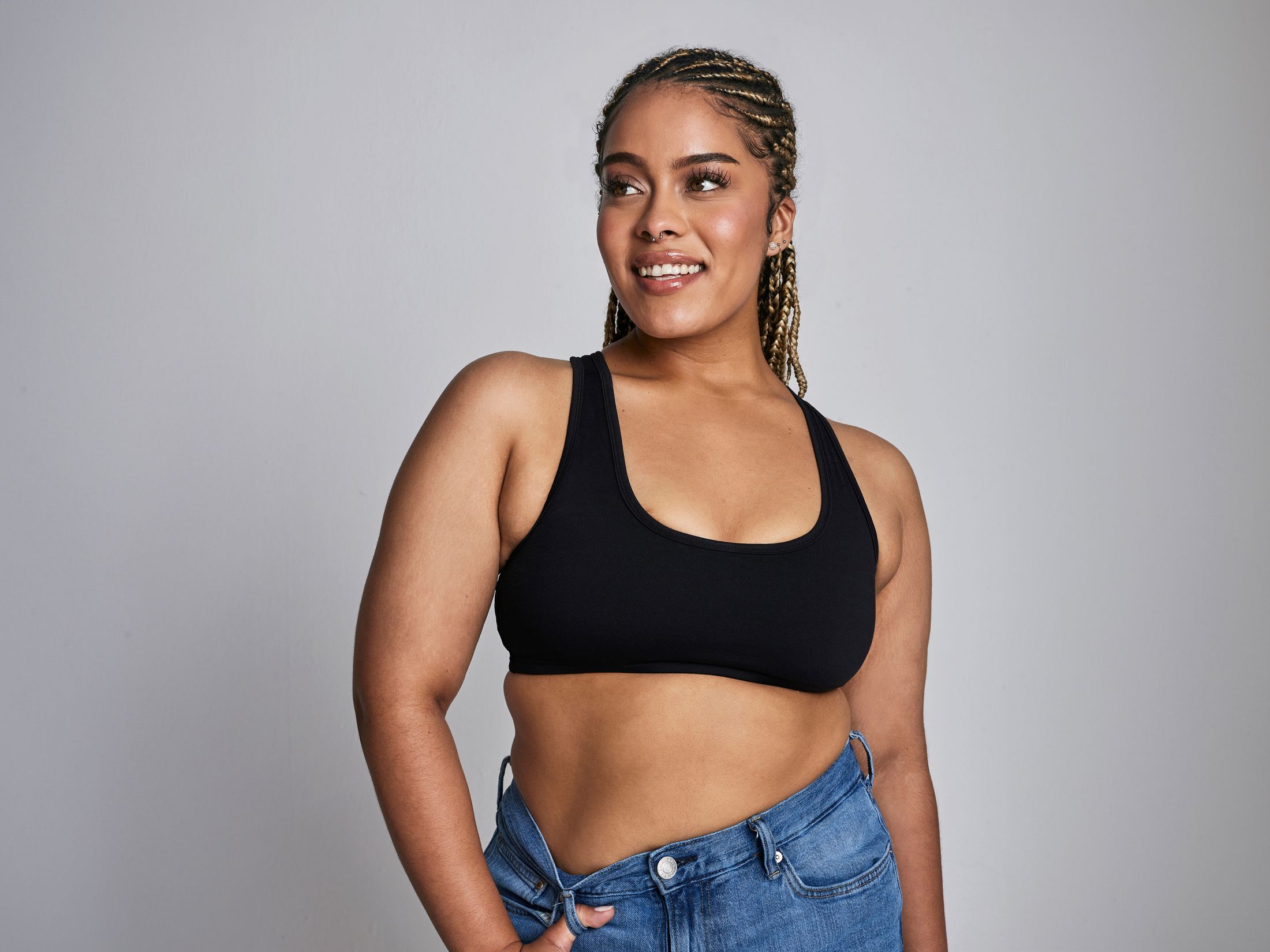 Smiling woman in black top and denim shorts.