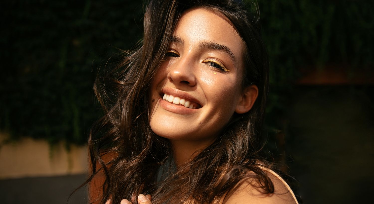 Smiling woman with flowing hair and golden accents.