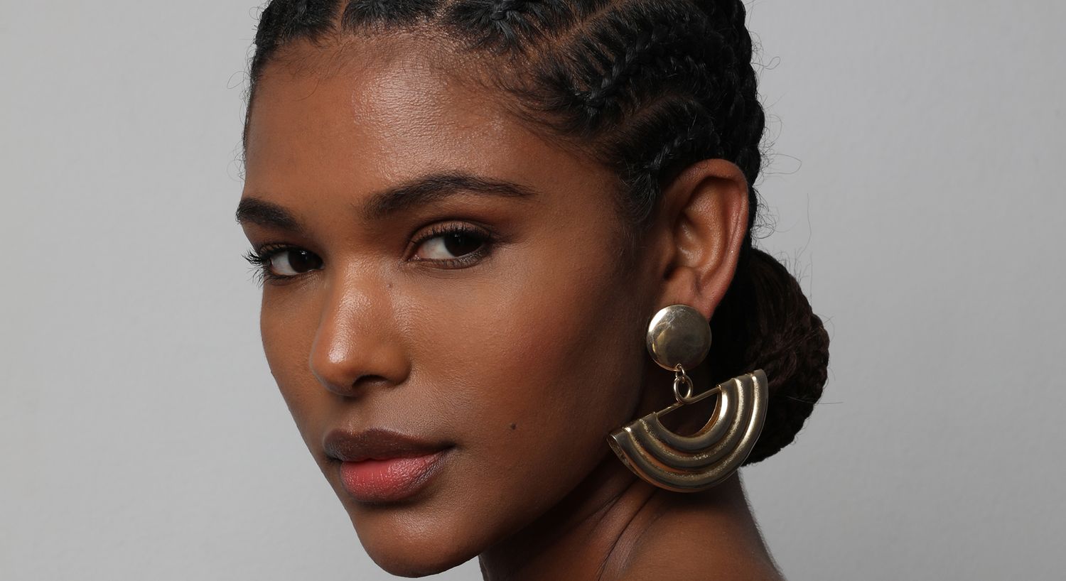 Woman with braided hair and statement earrings.