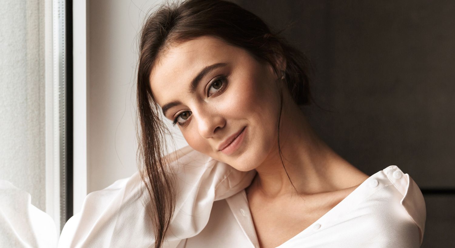 Woman smiling by a window in soft lighting